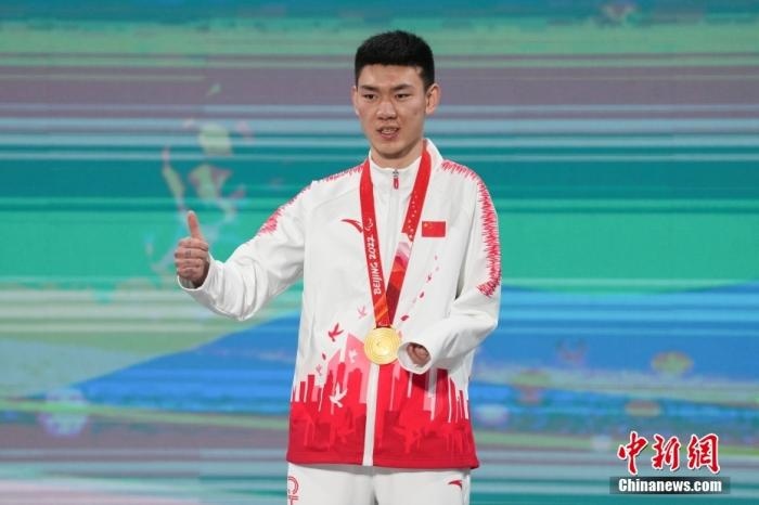 3月6日，梁景怡在延慶頒獎(jiǎng)廣場(chǎng)領(lǐng)獎(jiǎng)臺(tái)上豎起大拇指。當(dāng)日，在國(guó)家高山滑雪中心舉行的北京2022年冬殘奧會(huì)殘奧高山滑雪男子超級(jí)大回轉(zhuǎn)—站姿決賽中，中國(guó)選手梁景怡奪得冠軍。 <a target='_blank' href='/'>中新社</a>記者 楊華峰 攝