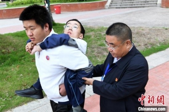 朱金祥背著鐘華強(qiáng)去教室上課的路上，也經(jīng)常碰到值班的校領(lǐng)導(dǎo)和老師前來(lái)搭把手。 卓忠偉 攝