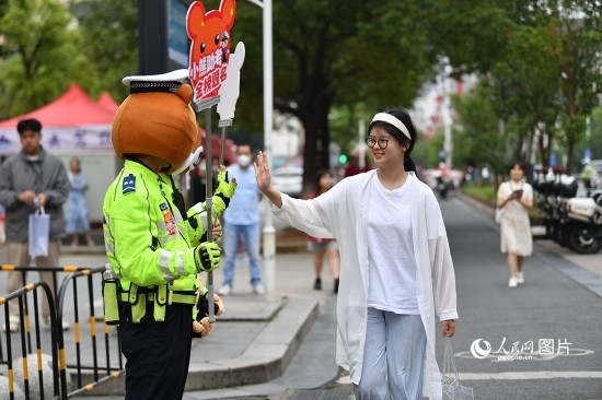 6月7日上午9時(shí)，隨著鈴聲的響起，2023年江西高考正式開考，江西省的53.57萬考生以縣（區(qū)）為單位隨機(jī)安排在全省256個(gè)考點(diǎn)、18968個(gè)考場參加高考。圖為“小熊交警”和考生擊掌鼓勵(lì)。 人民網(wǎng)記者 時(shí)雨攝