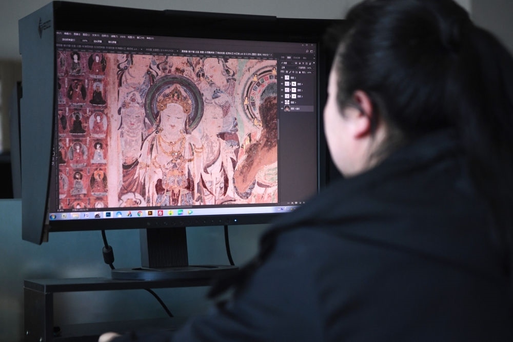 敦煌研究院文物數(shù)字化保護(hù)團(tuán)隊(duì)圖像處理人員年海麗在拼接壁畫圖像（2023年4月25日攝）。數(shù)字化探索為莫高窟的保護(hù)與傳承開辟了全新路徑，數(shù)字技術(shù)讓敦煌文物走出洞窟，跨出國門，走向“永久保存、永續(xù)利用”。新華社記者 陳斌 攝