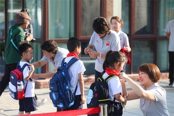 8月30日，雄安史家胡同小學(xué)學(xué)生體驗(yàn)學(xué)校生活。老師為學(xué)生佩戴校徽。