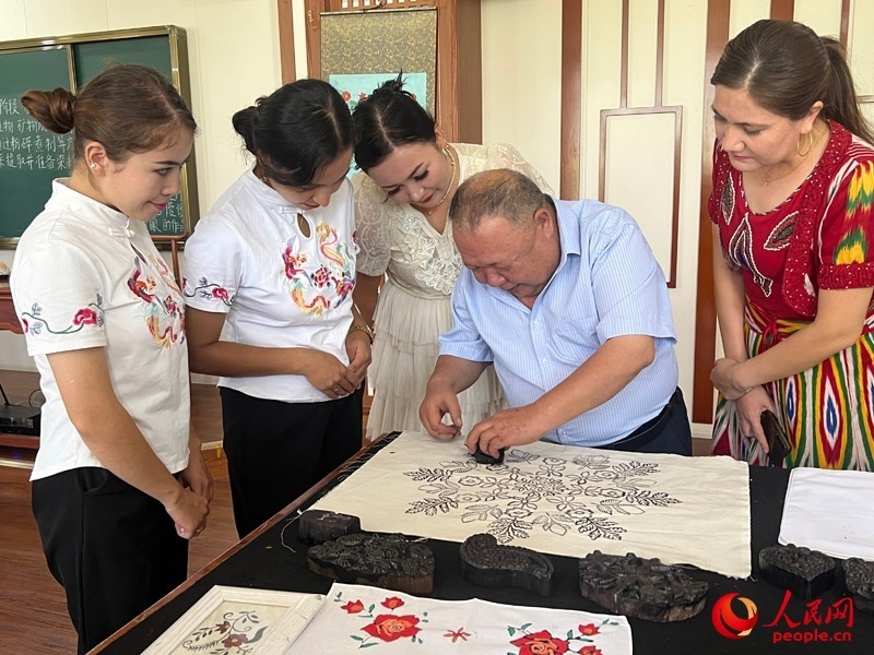 國家級非物質(zhì)文化遺產(chǎn)模戳印花布技藝傳承人吾吉阿西木?吾舒爾展示模戳印花布的制作過程。人民網(wǎng)記者 常雪梅攝