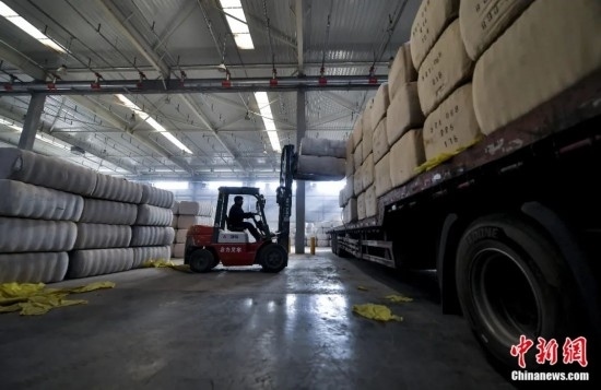 新疆喀什綜合保稅區(qū)，喀什啟路國際貿(mào)易有限公司的倉庫內(nèi)，工人正在裝載從塔吉克斯坦和烏茲別克斯坦進口的棉花。劉新攝
