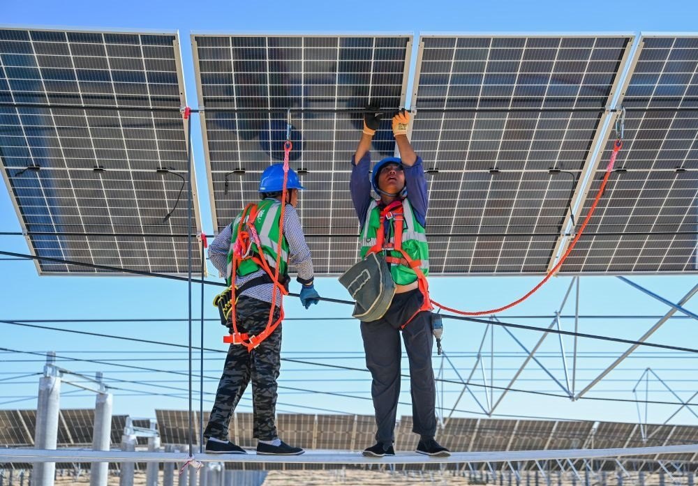 2023年7月22日，工人在位于內(nèi)蒙古杭錦旗庫布其沙漠億利生態(tài)示范區(qū)的蒙西基地庫布其200萬千瓦光伏治沙項(xiàng)目工地安裝光伏板。新華社記者 劉磊 攝