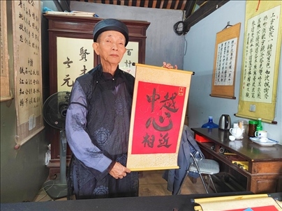 越南首都河內(nèi)文廟內(nèi)，阮明珠展示“中越心相近”書法作品。