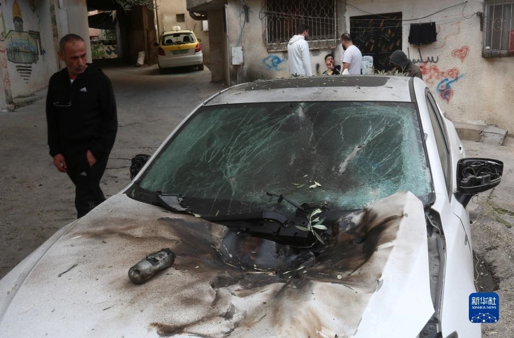 12月17日，在約旦河西岸城市圖勒凱爾姆附近的一處難民營，人們查看在沖突中損毀的車輛。新華社發(fā)（尼達爾·艾仕塔耶攝）