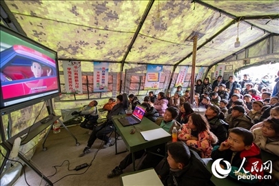 12月22日，在積石山縣大河家鎮(zhèn)大河村安置點，陸軍76集團軍某旅搭建的“臨時學(xué)校”內(nèi)，小朋友正在看動畫片。人民網(wǎng)記者 翁奇羽攝