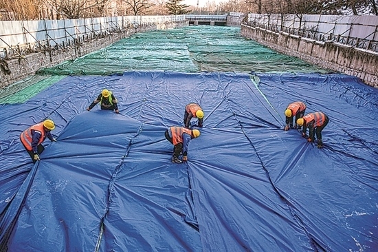 1月3日，房山區(qū)東風(fēng)街道，工人正在修復(fù)的河道內(nèi)給混凝土鋪設(shè)保溫布。