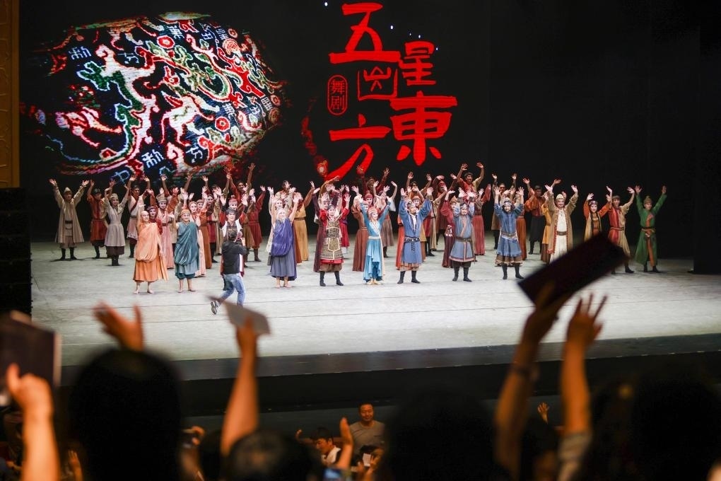 2023年7月31日，新疆和田地區(qū)新玉歌舞團(tuán)在烏魯木齊京劇院演出舞劇《五星出東方》后和觀眾互相揮手致意。這場(chǎng)演出是第六屆中國(guó)新疆國(guó)際民族舞蹈節(jié)的參演劇目之一，曾榮獲國(guó)家“文華獎(jiǎng)”等。新華社記者 郝昭 攝