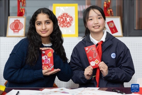 1月28日，美國馬斯卡廷中學學生（左）和復旦大學第二附屬學校學生展示互相送出的寫有寄語祝福的紅包。 新華社記者 王翔 攝