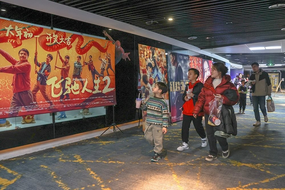 △ 2024年2月16日，在江西贛州一家電影院，觀眾從春節(jié)檔電影的宣傳展板前走過(guò)。