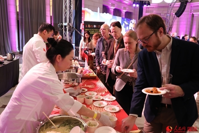 當(dāng)?shù)貢r(shí)間3月7日晚，華盛頓聯(lián)合車站廣場(chǎng)舉行駐美使團(tuán)“使館主廚挑戰(zhàn)賽”。圖為當(dāng)?shù)孛癖娫谥袊?guó)展臺(tái)前體驗(yàn)中國(guó)美食。人民網(wǎng)記者 李志偉攝