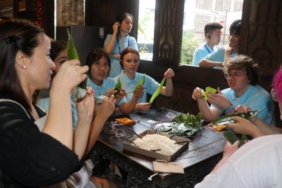 6月9日，美國青年代表在重慶永川松溉古鎮(zhèn)體驗包粽子。新華社記者 周思宇 攝