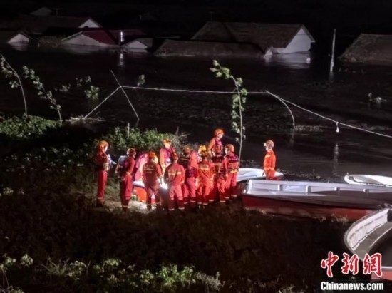  7月6日凌晨3時(shí)，在湖南岳陽(yáng)華容縣團(tuán)洲垸洞庭湖一線堤防，救援人員剛剛完成一次救援任務(wù)，遠(yuǎn)處是被淹的民房。中新社記者 白祖偕 攝