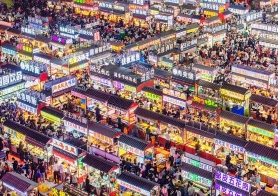 2024年4月21日，人們?cè)诤颖笔≌h小商品夜市品嘗美食（無(wú)人機(jī)照片）。新華社發(fā)（武志偉 攝）