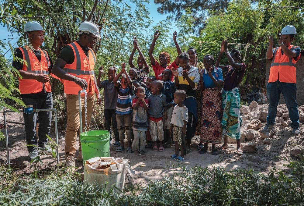 2023年6月13日，在坦桑尼亞姆萬扎省米松圭，工作人員接通水管后贏得當(dāng)?shù)鼐用窆恼茪g呼。新華社記者 王冠森 攝