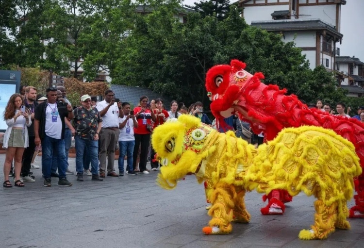 2024“一帶一路”媒體合作論壇聯(lián)合采訪調(diào)研行成員在樂山蘇稽古鎮(zhèn)觀看非遺舞獅表演。本報(bào)記者 伊霄攝