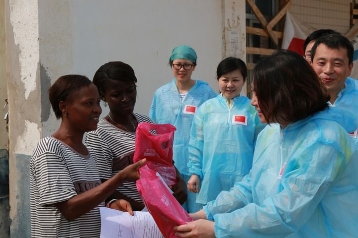 2015年4月4日，在位于塞拉利昂首都弗里敦市郊的中塞友好醫(yī)院埃博拉診療中心，中國(guó)第四批援塞醫(yī)療隊(duì)副隊(duì)長(zhǎng)邵蔚（右前）向被治愈的埃博拉出血熱患者贈(zèng)送禮物。新華社發(fā)（祖榮強(qiáng) 攝）