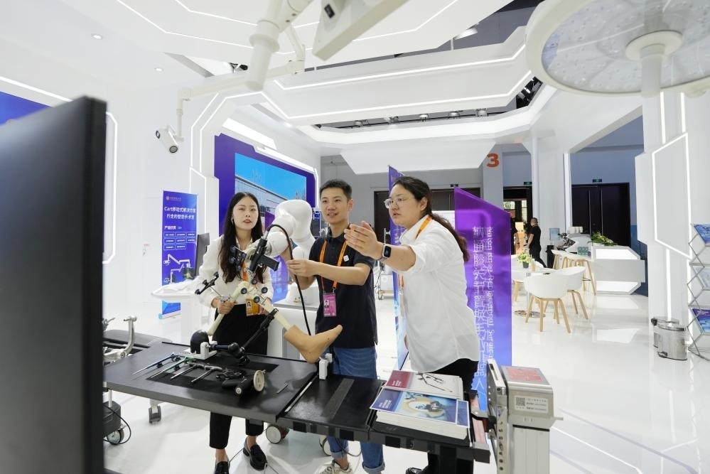 9月11日，一位媒體記者（中）在2024年服貿(mào)會國家會議中心會場體驗北京納通科技集團有限公司的膝關節(jié)置換手術機器人。新華社記者鞠煥宗 攝