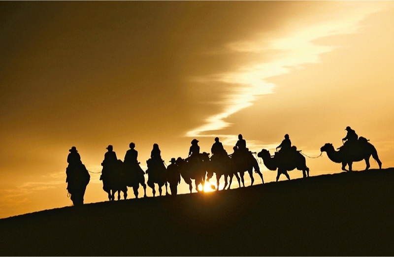 新時代以來，文化和旅游深度融合發(fā)展體制機(jī)制不斷健全，成功走出了一條獨(dú)具特色的中國旅游發(fā)展之路。圖為2024年9月1日清晨，游客在甘肅省敦煌市鳴沙山月牙泉景區(qū)乘騎駱駝，欣賞大漠風(fēng)光，體驗(yàn)絲路風(fēng)情。 新華社發(fā) 張曉亮/攝