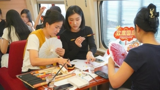 10月1日，旅客們?cè)贕1634次列車上給油紙傘作畫。新華社記者周義 攝