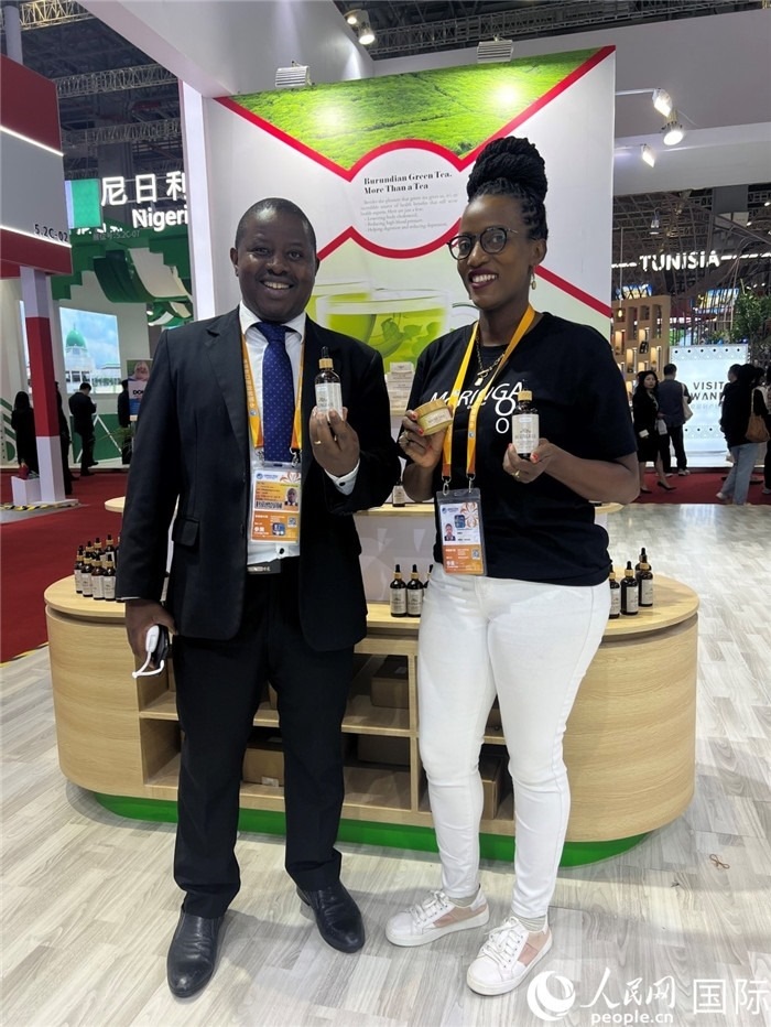 6月6日，布隆迪駐華大使館一等參贊布利馬索·阿爾弗雷德 (左，Bulimaso Alfred) 和參展商卡馬里扎·埃斯特拉 (Kamariza Estella) 在第七屆中國國際進(jìn)口博覽會布隆迪館展示當(dāng)?shù)厣a(chǎn)的辣木油。（人民網(wǎng) 艾里士 攝）