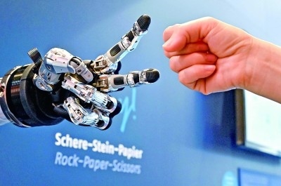 在德國漢諾威工博會上，參觀者與一款智能機(jī)器人進(jìn)行“石頭剪子布”游戲。新華社發(fā)