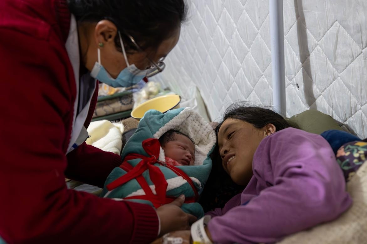 1月10日，定日縣中心醫(yī)院的婦產(chǎn)科醫(yī)生悉心照看一位母親和她懷里的新生兒。人民日報(bào)記者張武軍攝