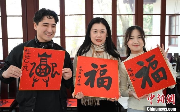 1月20日，外籍留學(xué)生和西泠印社社員李硯(中)展示各自創(chuàng)作的福貼。當(dāng)日，來自巴西、馬來西亞、加納、哈薩克斯坦的外籍留學(xué)生在浙江杭州西泠印社體驗福貼、春聯(lián)和篆刻，感受古老的中國傳統(tǒng)文化。中新社記者 王剛 攝