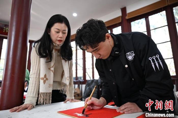 1月20日，外籍留學(xué)生在西泠印社社員李硯指導(dǎo)下寫福。當(dāng)日，來自巴西、馬來西亞、加納、哈薩克斯坦的外籍留學(xué)生在浙江杭州西泠印社體驗福貼、春聯(lián)和篆刻，感受古老的中國傳統(tǒng)文化。中新社記者 王剛 攝