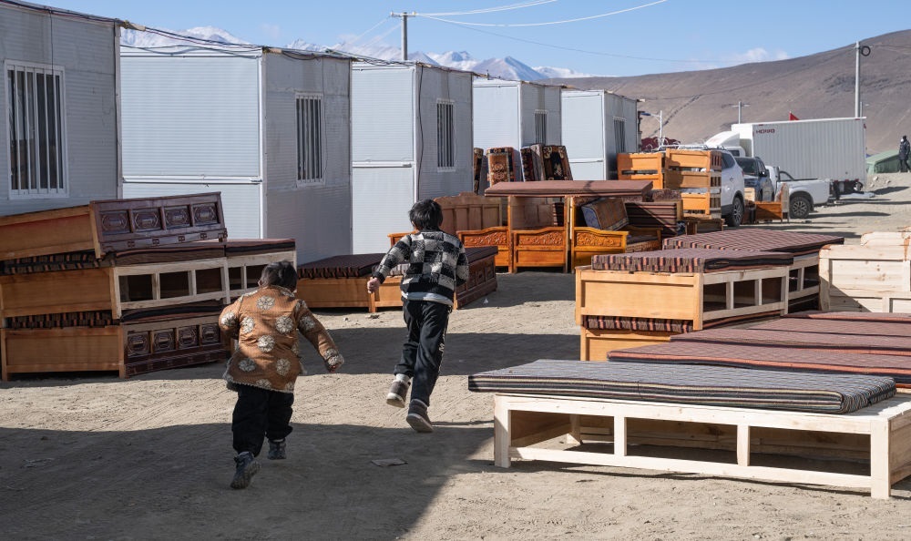 2025年1月13日，在定日縣嘎旦村，兩個(gè)孩子在剛運(yùn)來的兩排藏床間奔跑。新華社記者丁增尼達(dá) 攝