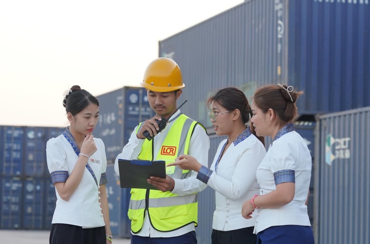 萬象南站貨運值班員陳尼啦（左一）與同事在一起討論工作。老中鐵路有限公司供圖