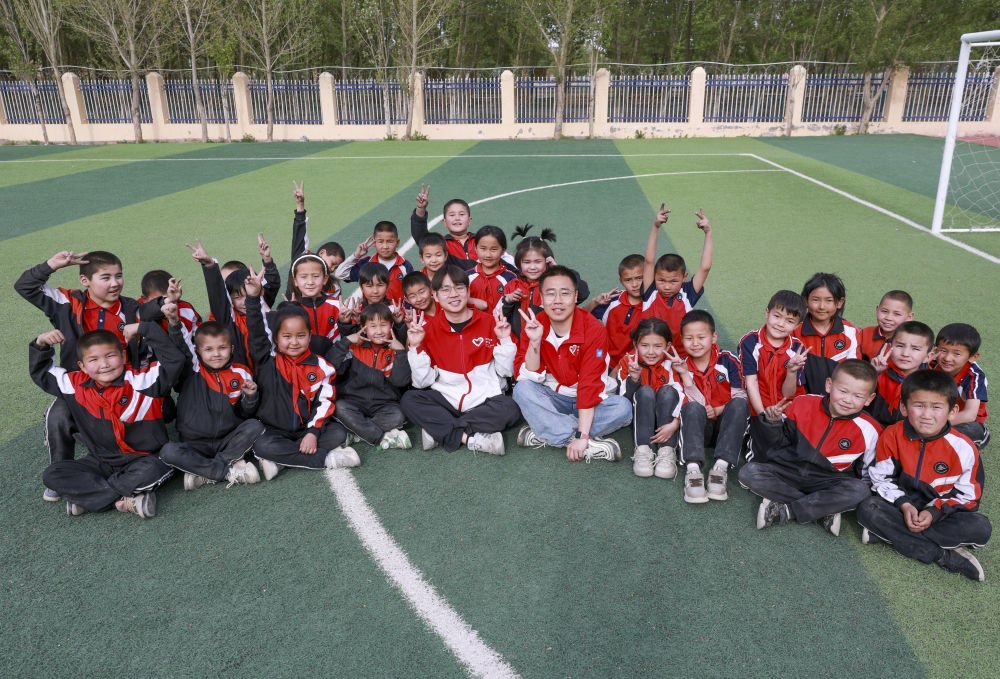 4月23日，在新疆克州阿圖什市哈拉峻鄉(xiāng)謝依特小學(xué)，支教教師王俊文（中左）、李軻凡（中右）和學(xué)生在一起。